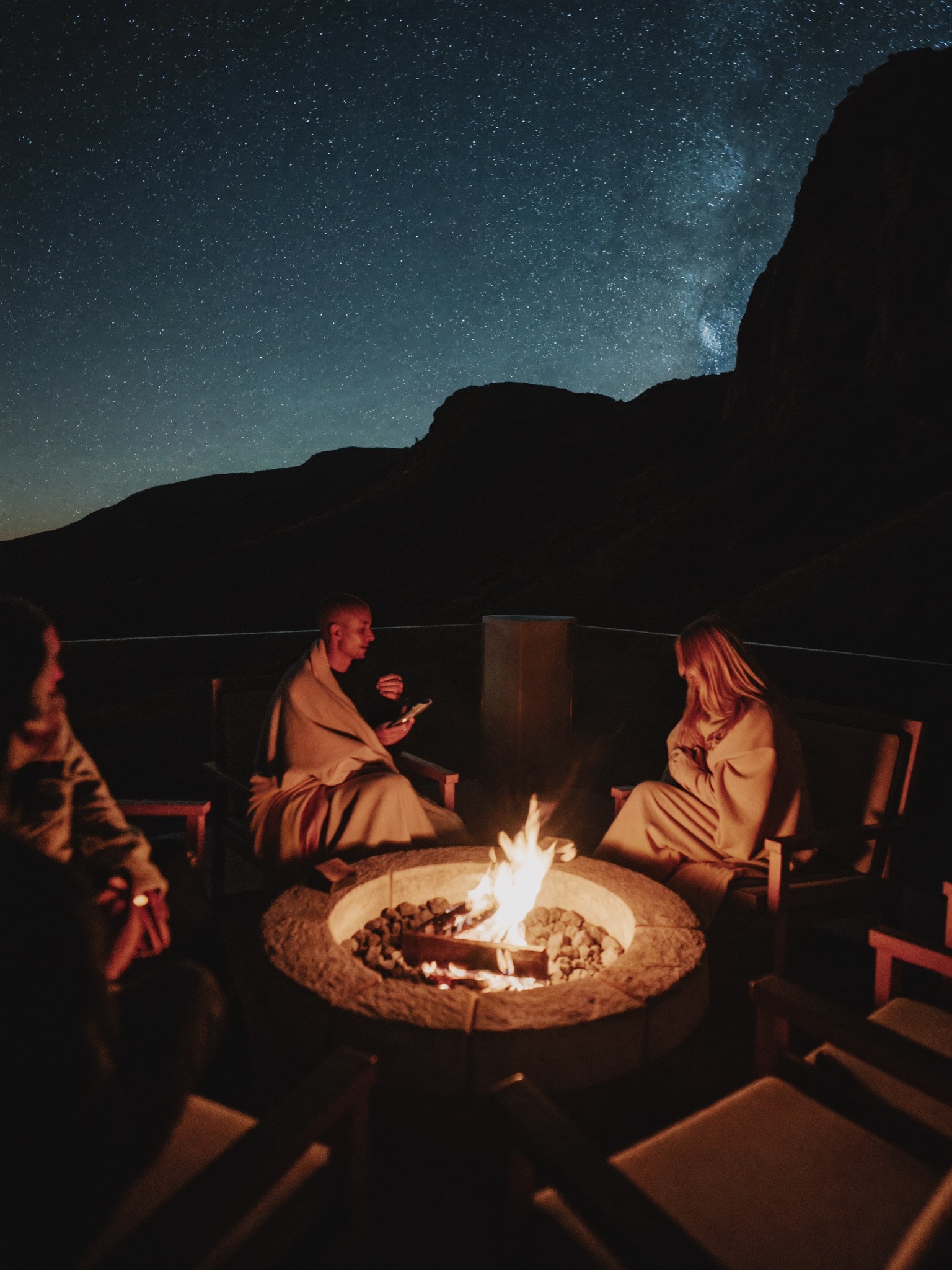 Guests around a stone fire pit under a starry sky