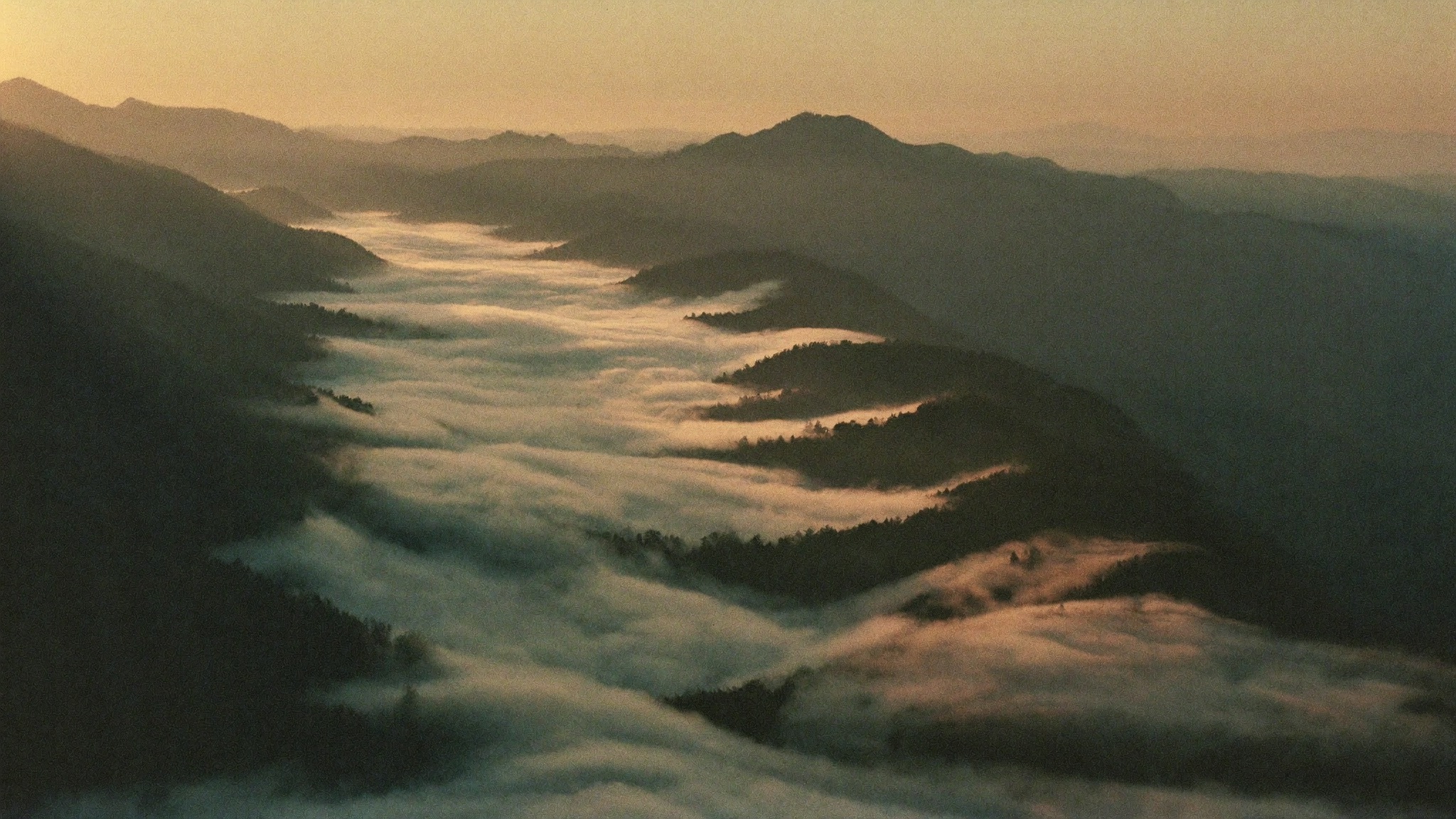 Layered mountain ridgelines at dawn with mist filling the valleys